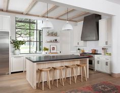 a kitchen with white cabinets and black counter tops next to an island in the middle