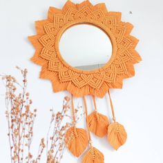 an orange wall hanging with tassels and a mirror