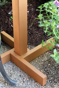 a pair of scissors sitting on the ground next to a wooden post and planter