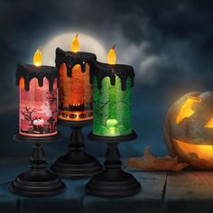 three halloween candles sitting on top of each other in front of a full moon and pumpkin