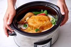 a close up of a person holding an open crock pot filled with food