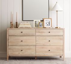 a wooden dresser sitting next to a white wall with a large mirror on top of it