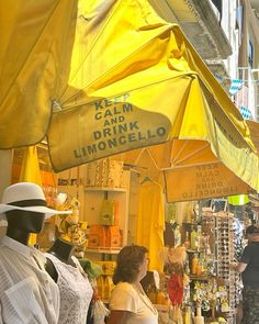 people are standing under umbrellas in an outdoor market area with yellow drapes covering the tables