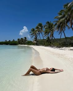 a woman laying on the beach with palm trees in the backgroung and clear water