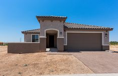 a house in the middle of a desert with no grass on the ground and blue sky above it