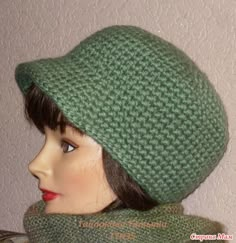 a mannequin head wearing a green knitted hat and scarf