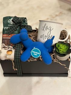 a blue dog toy sitting on top of a box filled with coffee and other items