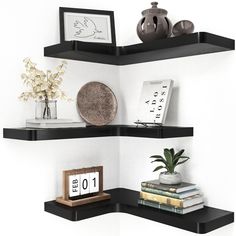 two black shelves with books and vases on top of each shelf in the corner