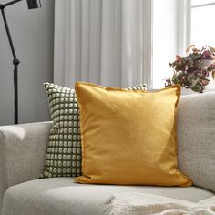 a couch with two pillows on it and a plant in the corner next to it