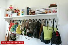 several purses are hanging on a white shelf with books and toys in the background