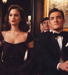 two people in tuxedos are sitting next to each other and one person is looking at the camera