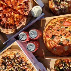 several pizzas and cans of soda sit on the table top, including one with pepperoni