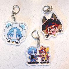 three keychains with cartoon characters on them sitting on a white counter top next to each other