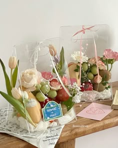 two vases filled with flowers on top of a wooden table next to a card