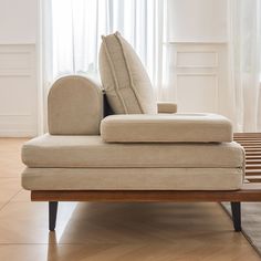 a beige couch sitting on top of a hard wood floor next to a wooden table