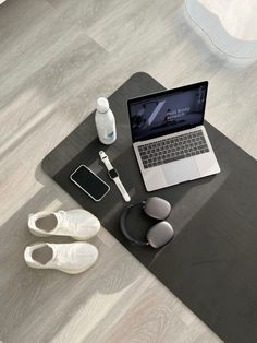 an open laptop computer sitting on top of a wooden table next to a pair of white shoes