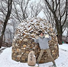 a man standing next to a stone structure in the snow