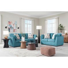 a living room filled with blue couches and pillows on top of a white rug