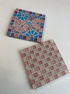 two pieces of colorful tile sitting on top of a white table next to each other