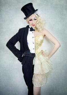 a woman in a tuxedo and top hat posing for the camera with her hands on her hips