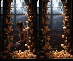 a woman standing in front of a mirror with flowers on it's sides and the reflection behind her