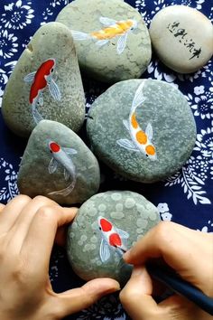 someone is painting rocks with goldfish on them