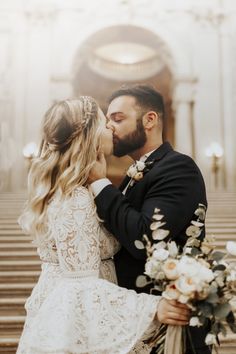 a bride and groom kissing in front of stairs