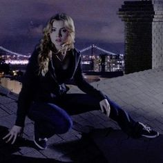 a woman sitting on top of a roof next to a fire hydrant at night