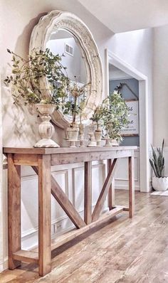 a wooden table topped with potted plants next to a mirror