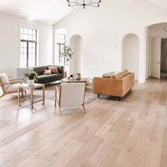 a living room filled with furniture and lots of windows on top of wooden flooring