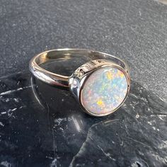 Lightning Ridge Australia opal ring set in 14K yellow gold.  Round Australian opal bezel set 14k gold ring. Lightning Ridge opal - 1.16 carats, 8.60mm X 8.63mm 14K Solid 14k gold construction, band 2.5mm X 1.25mm Currently US 7 3/4 for reference (select size at checkout) All of our creations are made out of 14K Gold (Yellow, White, Rose) or 925 Sterling Silver, None are filled or electroplated.  All of our stones are Nature-made, therefore some natural flaws may be present. Hand crafted in the W Black Opal Ring With Cabochon As A Gift, Adjustable Round Opal Ring, Spiritual Style, Black Opal Round Jewelry, Boulder Opal Ring, Lightning Ridge Black Opal, Lightning Ridge Opal, Australian Black Opal, Opal Band, Lightning Ridge