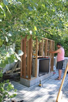 a man standing on a deck next to a tv set in the middle of trees