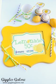 a lemonade sign is surrounded by cupcakes and candy