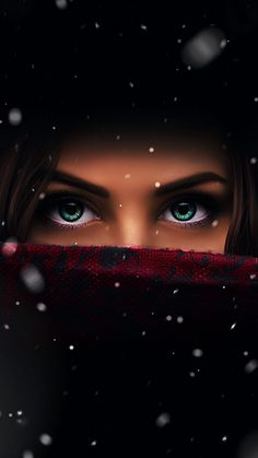 a woman's eyes are covered in snow as she hides her face behind a blanket