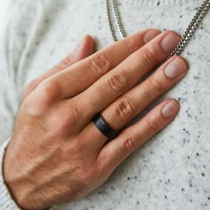 a man's hand with a black ring on his finger and a chain attached to it