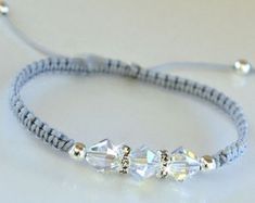 a bracelet with three crystal beads and silver thread on a white tablecloth background,