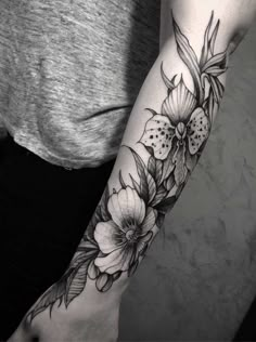 a woman's arm with black and white flowers on the left side of her arm