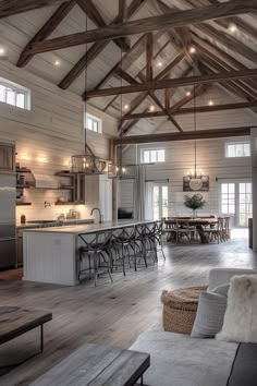 a large open concept kitchen and living room with wood beams on the ceiling, white walls and wooden flooring