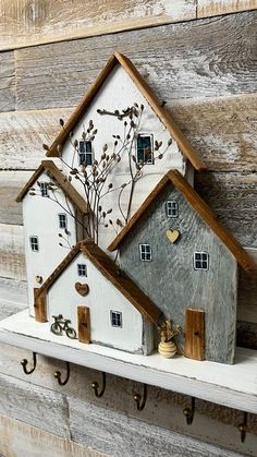 two white houses are sitting on a shelf with hooks and keys in front of them