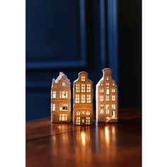 three lit up houses sitting on top of a wooden table