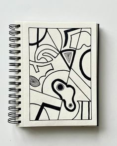 a black and white drawing on top of a spiral notebook with an abstract design in the middle