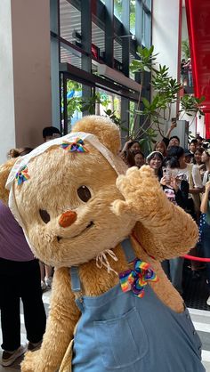 a large teddy bear dressed in overalls and headbands standing on the street