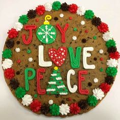 a cookie decorated with the words joy love peace and a christmas ornament on it