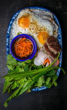 an egg, meat and vegetables on a blue plate