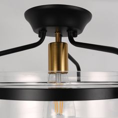 a black and gold chandelier with a light bulb on the bottom, in front of a white background