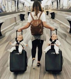 a woman with two baby dolls pulling luggage