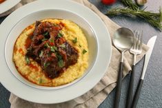 a white plate topped with mashed potatoes covered in meat and garnished with parsley