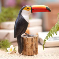 a toucan sitting on top of a wooden stump next to a flower pot