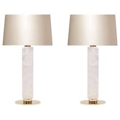 a pair of clear glass table lamps with gold base and linen shades on each lamp