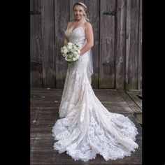 a woman in a wedding dress standing on a wooden deck holding a bouquet of flowers